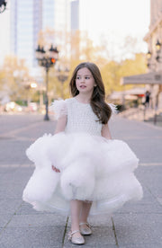 White, asymmetrical girl dress with a voluminous, ruffle tulle skirt, feather details and pearl embellished top. Occasions: Wedding, Birthday party, Flower girl, Communion, Eid and other events.