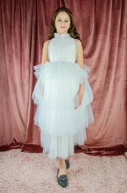 Ankle-length tulle girl dress with a multi-layered tulle skirt, tulle pleated top with a high collar and pearl embellishments along the neckline and the waistline.