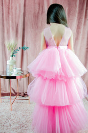 Asymmetrical high-low hem girl princess dress in bright pink with a multi-layer tulle skirt, satin top, open back and a pink bow.
