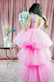 Asymmetrical high-low hem girl princess dress in bright pink with a multi-layer tulle skirt, satin top, open back and a pink bow.