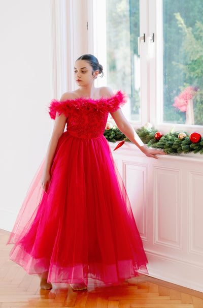 Festive, floor length princess ball gown in bright pink, with a long, voluminous tulle skirt, satin top with embroidery and off-the-shoulder neckline with tulle ruffles and feather details. For special occasions: Christmas, New Year's Eve, Wedding, Birthday party, Prom, Flower girl, Eid, and other events.