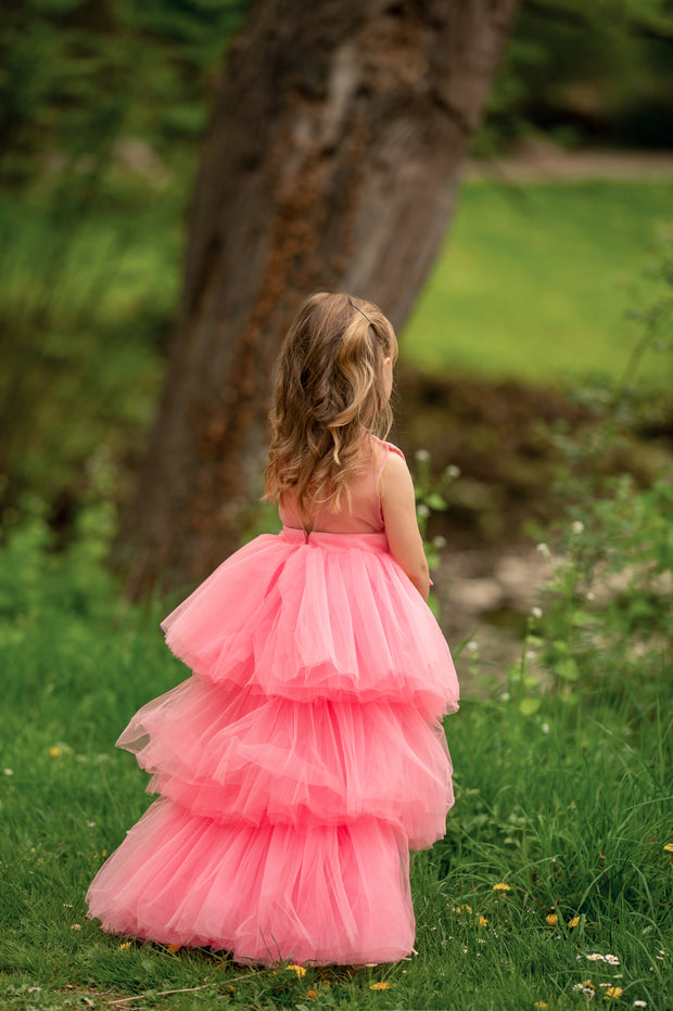 Asymmetrical high-low hem girl princess dress in bright pink with a multi-layer tulle skirt, satin top, open back and a pink bow.