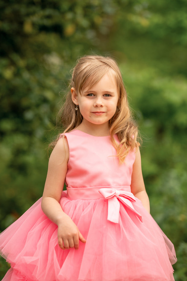 Asymmetrical high-low hem girl princess dress in bright pink with a multi-layer tulle skirt, satin top, open back and a pink bow.