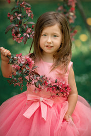 Asymmetrical high-low hem girl princess dress in bright pink with a multi-layer tulle skirt, satin top, open back and a pink bow.