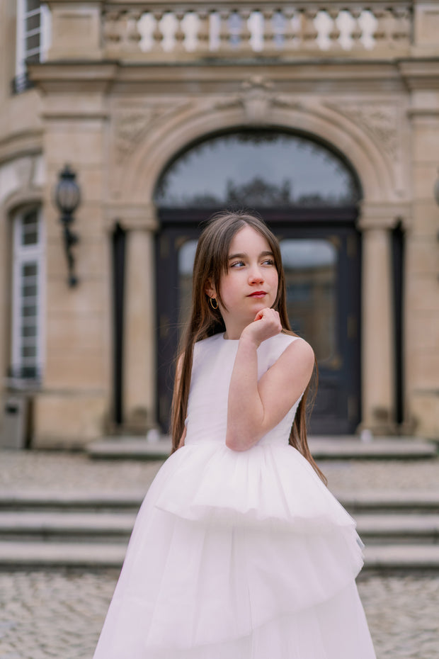 Long, a-line flower girl tulle dress in white with long, asymmetrical tulle skirt and sleeveless pleated tulle top. Handmade with love. Occasions: First Communion, Flower girl, Wedding, Birthday party, and other events. 