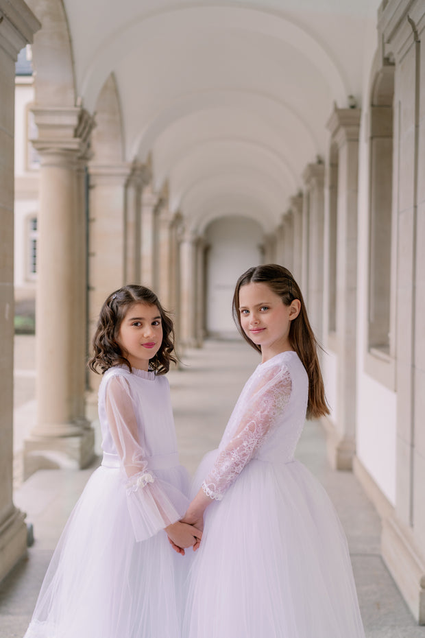 Long, a-line tulle boho style first communion, flower girl dress in white with long tulle skirt and lace details, high collar, buttons at the back and long transparent sleeves with lace details. Handmade with love. Occasions: First Communion, Flower girl, Wedding, Birthday party, and other events.