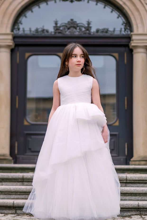 Long, a-line flower girl tulle dress in white with long, asymmetrical tulle skirt and sleeveless pleated tulle top. Handmade with love. Occasions: First Communion, Flower girl, Wedding, Birthday party, and other events. 