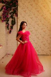 Floor length princess ball gown in bright pink, with a long, voluminous tulle skirt, satin top with embroidery and off-the-shoulder neckline with tulle ruffles and feather details. For special occasions: Wedding, Birthday party, Prom, Flower girl, Eid, and other events.