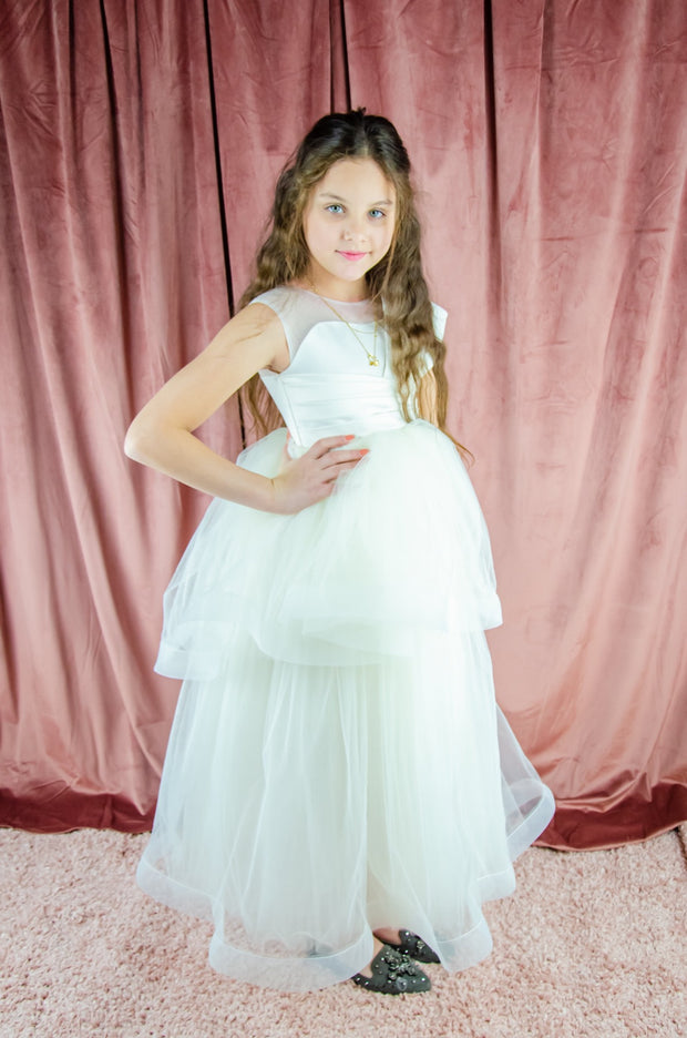 Long, white A-line flower girl dress with an asymmetrical multi-layer tulle skirt and white satin top with pleated satin details.