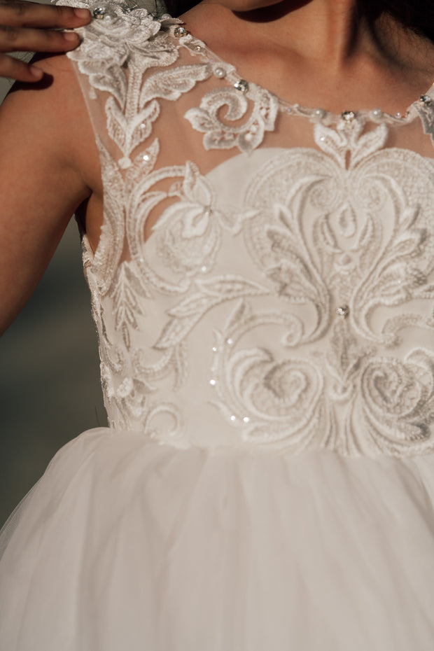 Enchanting princess dress in white with a voluminous, long tulle skirt,satin top with intricate lace embroidery, open back and pearl details.