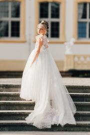 Long flower girl dress in white with a long, tulle train, lace embroidery, open back with lace and a big bow. For special occasions: Wedding, Birthday party, Prom, Flower girl, Eid, and other events.