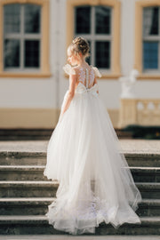 Long flower girl dress in white with a long, tulle train, lace embroidery, open back with lace and a big bow. For special occasions: Wedding, Birthday party, Prom, Flower girl, Eid, and other events.