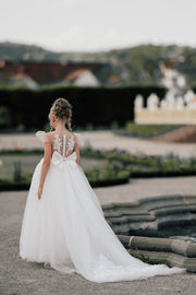 Long flower girl dress in white with a long, tulle train, lace embroidery, open back with lace and a big bow. For special occasions: Wedding, Birthday party, Prom, Flower girl, Eid, and other events.