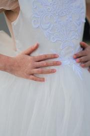 Long flower girl dress in white with a long, tulle train, lace embroidery, open back with lace and a big bow. For special occasions: Wedding, Birthday party, Prom, Flower girl, Eid, and other events.