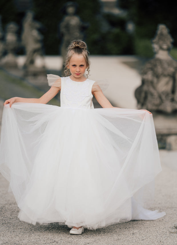 Long flower girl dress in white with a long, tulle train, lace embroidery, open back with lace and a big bow. For special occasions: Wedding, Birthday party, Prom, Flower girl, Eid, and other events.