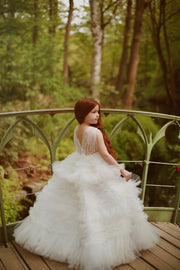 Enchanting fairy tale princess look with a long, white ball gown with voluminous skirt with tulle ruffles and open back. Occasions: Wedding, Birthday party, Prom, Flower girl, Eid, and other events.