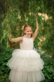 Ankle-length tulle girl dress with a multi-layered tulle skirt, tulle pleated top with a high collar and pearl embellishments along the neckline and the waistline.