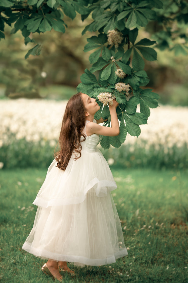 Long, white A-line flower girl dress with an asymmetrical multi-layer tulle skirt and white satin top with pleated satin details. Princess tulle girl dress for special occasions: girl birthday party, wedding, flower girl dress, junior bridesmaid, prom, communion, Eid.