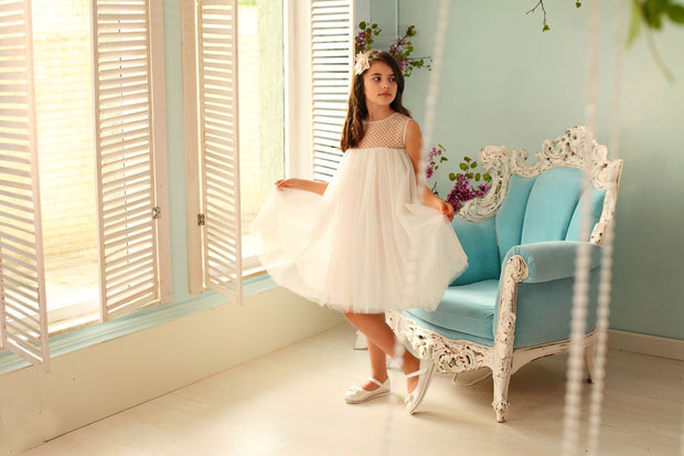 Knee-length white flower girl dress with empire silhouette, transparent mesh details and 3D floral embroidery in gold. The dress is for weddings, birthdays, parties, flower girls and other special formal events and occasions.