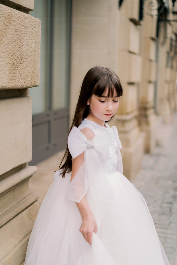 Long, white princess girl dress with a long, voluminous tulle skirt, embroidered top and big bows on the sleeves. For special occasions: flower girls, weddings, princess birthday party.