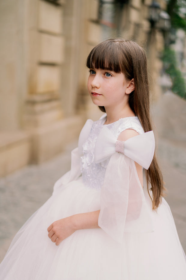Long, white princess girl dress with a long, voluminous tulle skirt, embroidered top and big bows on the sleeves. For special occasions: flower girls, weddings, princess birthday party.
